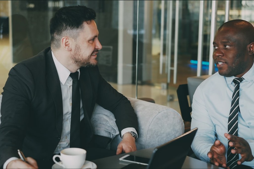 Two businessmen in suits having a focused leadership conversation at a conference table