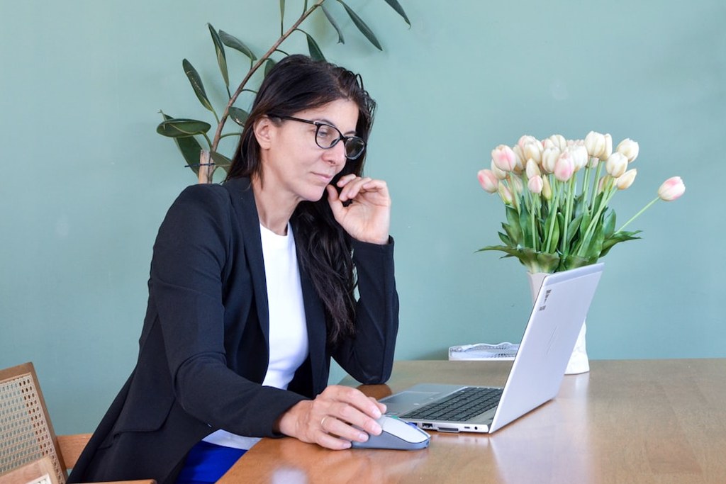 Woman in glasses at desk on laptop embracing leadership mindset transformation
